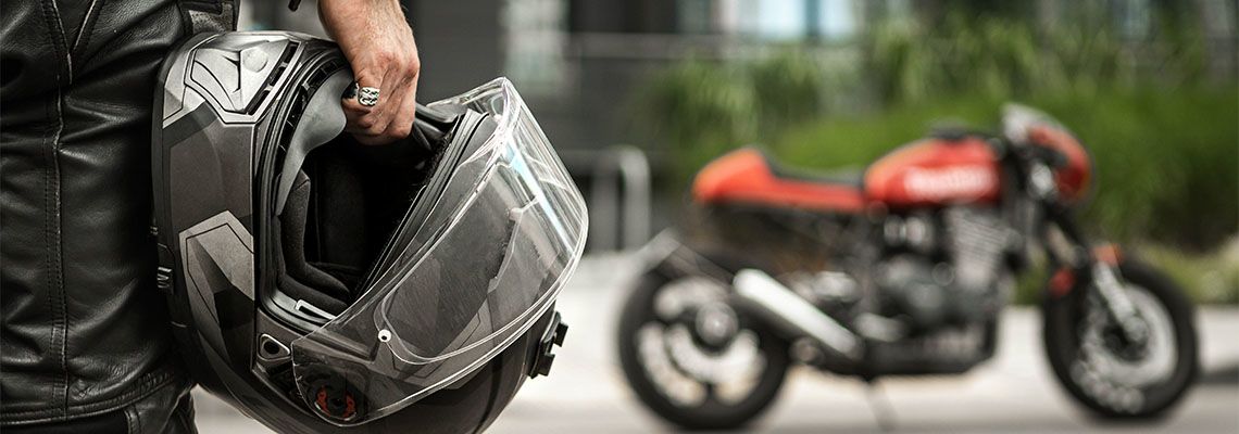 Biker walking towards motorcycle holding helmet in hand
