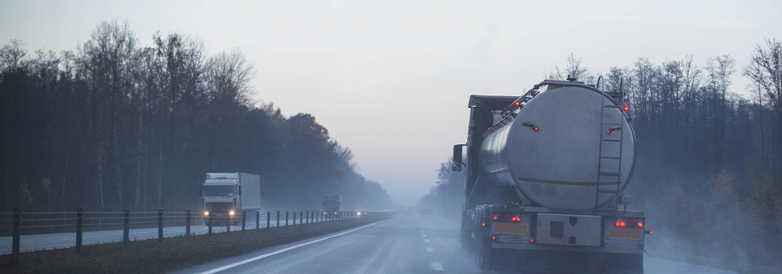 A truck wagon rides on a motorway in fog and rain