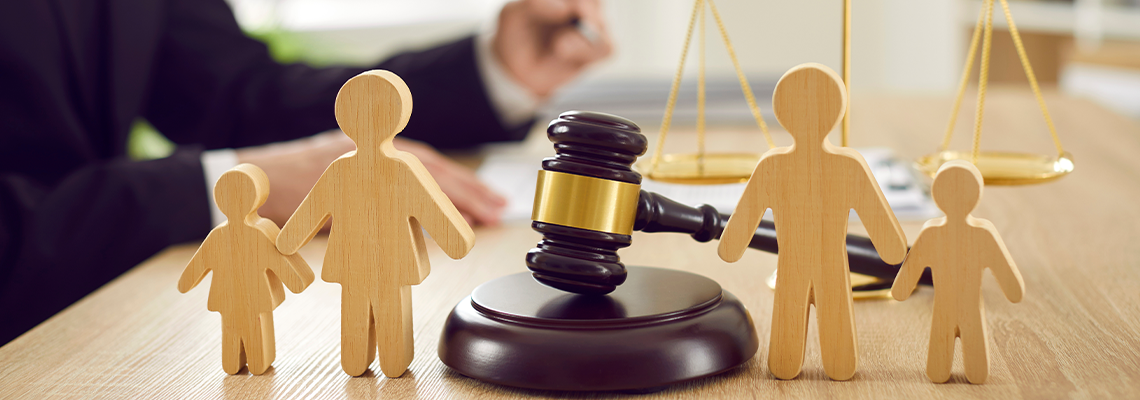 Gavel, sound block and little wooden figures of parents and children placed