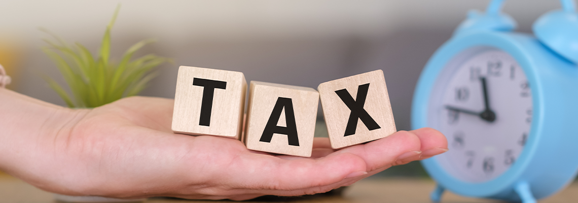 Hand holding wooden cubes of text TAX on the table