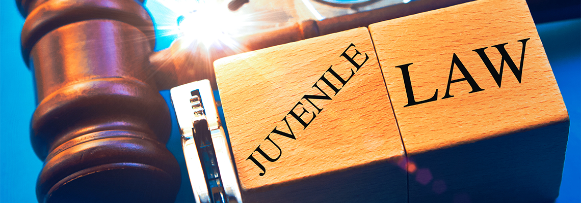 'Juvenile law' word with gavel and handcuffs on a blue background