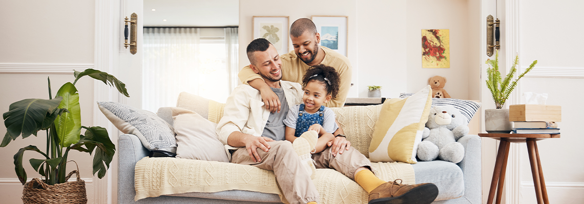 Gay, happy family and a child on a sofa at home with love, care and safety