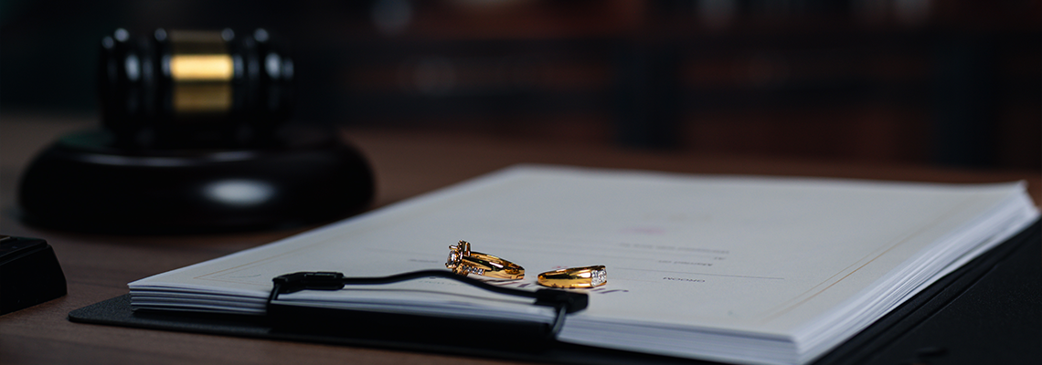 Gold divorce ring resting over paperwork marks official divorce filings
