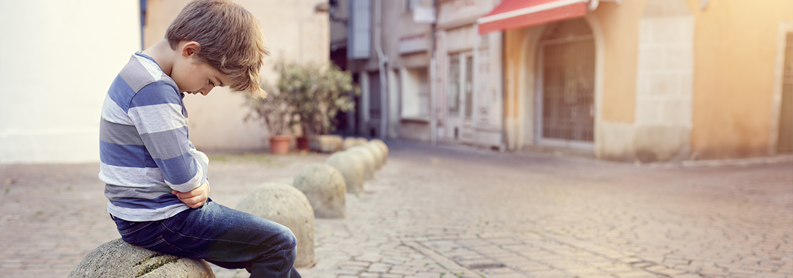 Lonely child sitting on a street corner