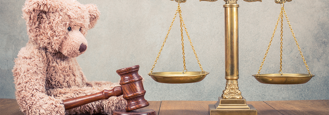 Bronze law scales and Teddy Bear with wooden gavel on table