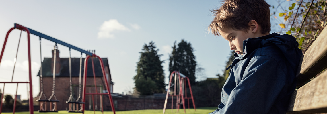 Lonely child with depression sitting on play park playground bench