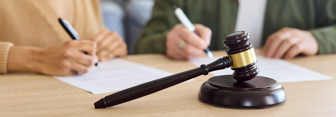 Couple sign divorce document beside court gavel