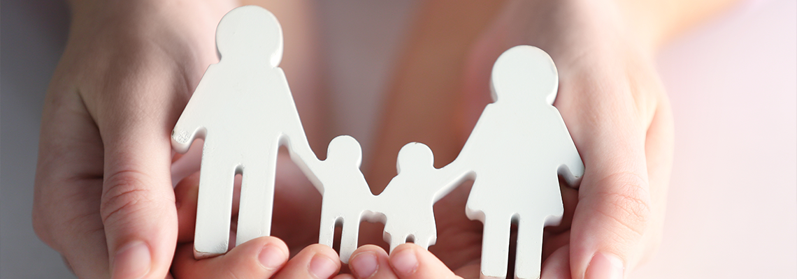 Child and adult person holding figure in shape of happy family