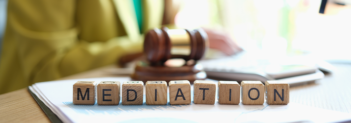 Mediator sitting near gavel of judge and words mediation closeup