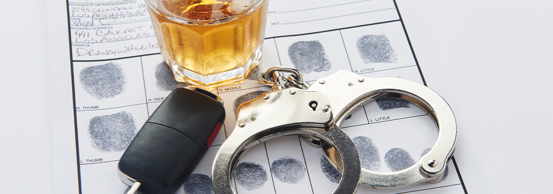 Handcuffs with fingerprints keys and glass of alcohol on ice