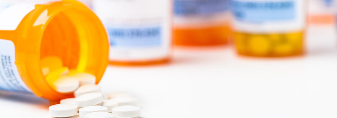 Round white prescription medication medicine pill tablets spilling from a bottle