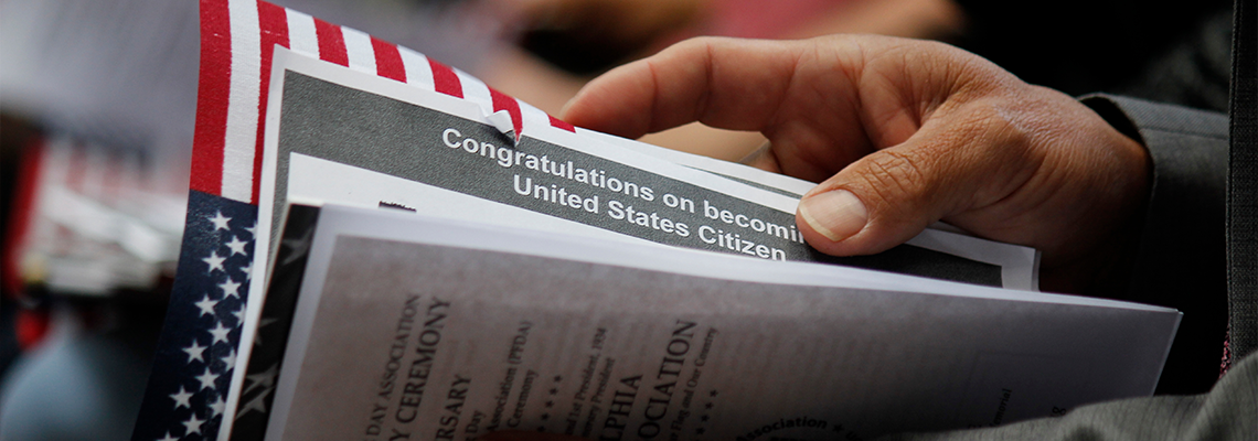 Immigrant's hand as he holds official welcome documents during the naturalization ceremony