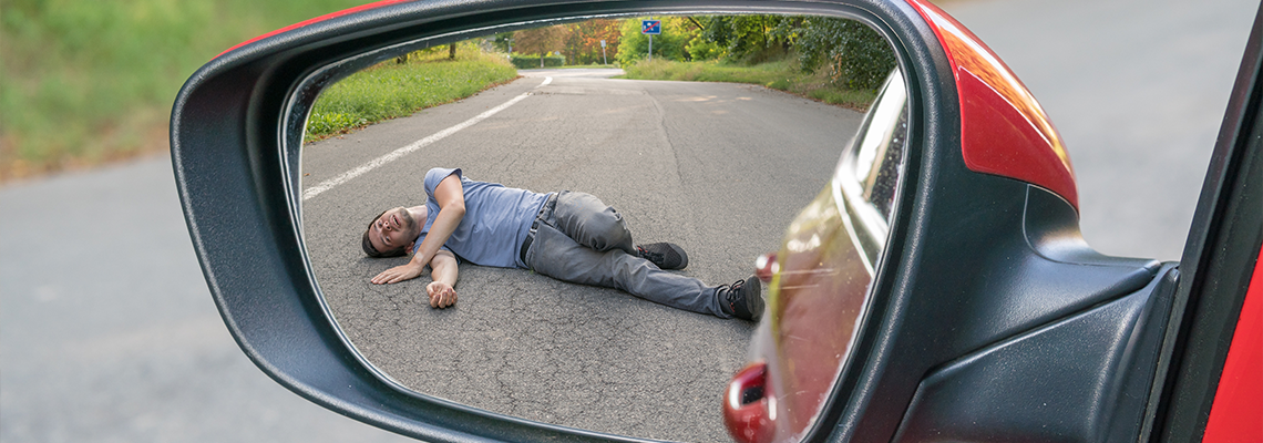 View on injured man on road in rear mirror of a car