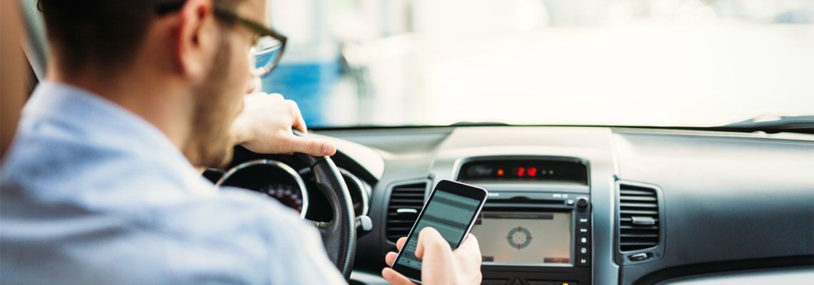 Man, texting on phone while driving car
