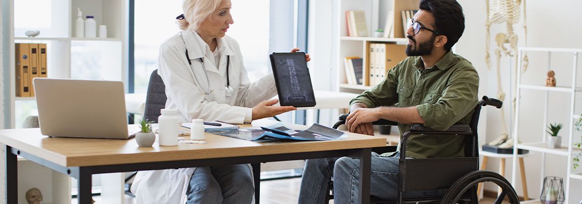 Senior doctor showing Spinal Xray to man in wheelchair