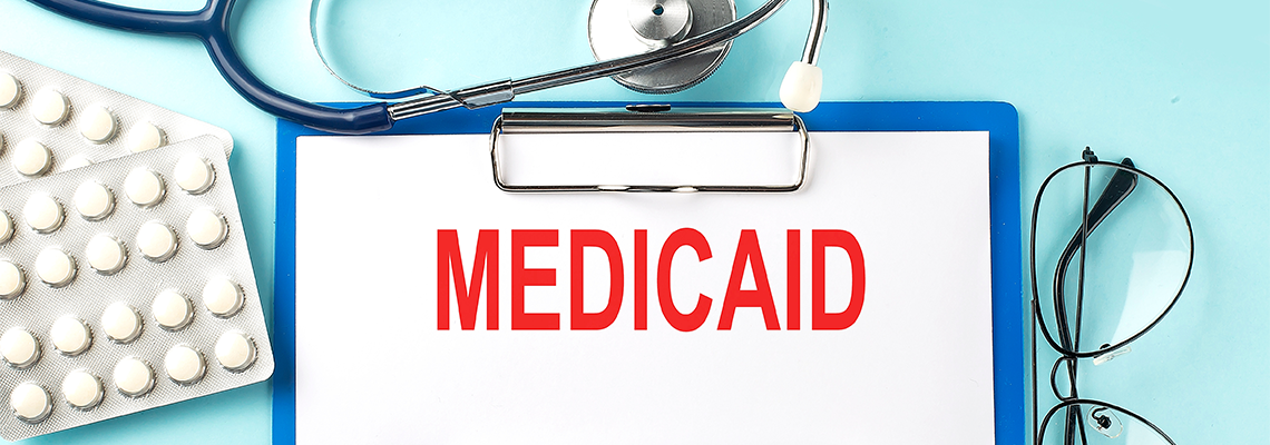 Paper with text MEDICAID on a blue background with stethoscope and pills
