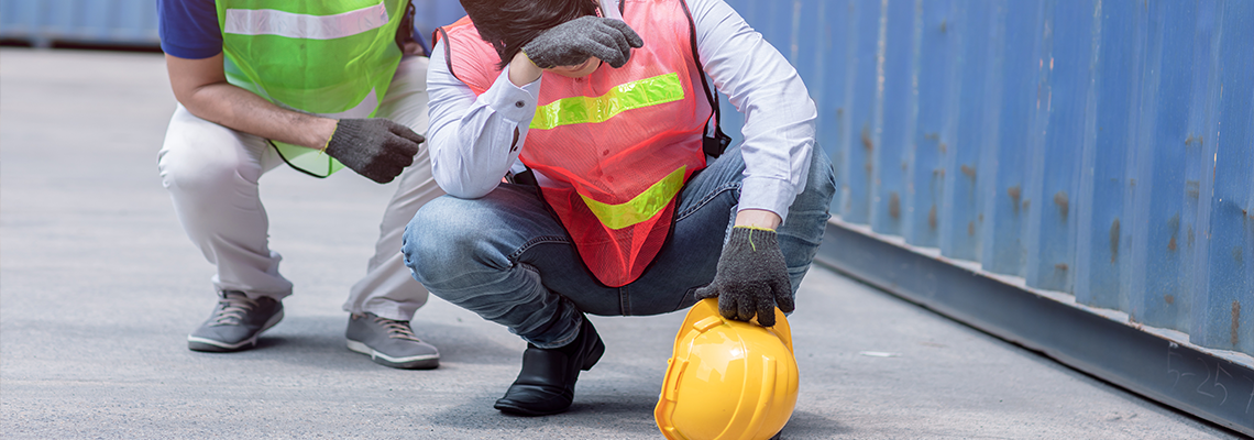 Person with hardhat and orange vest kneeling