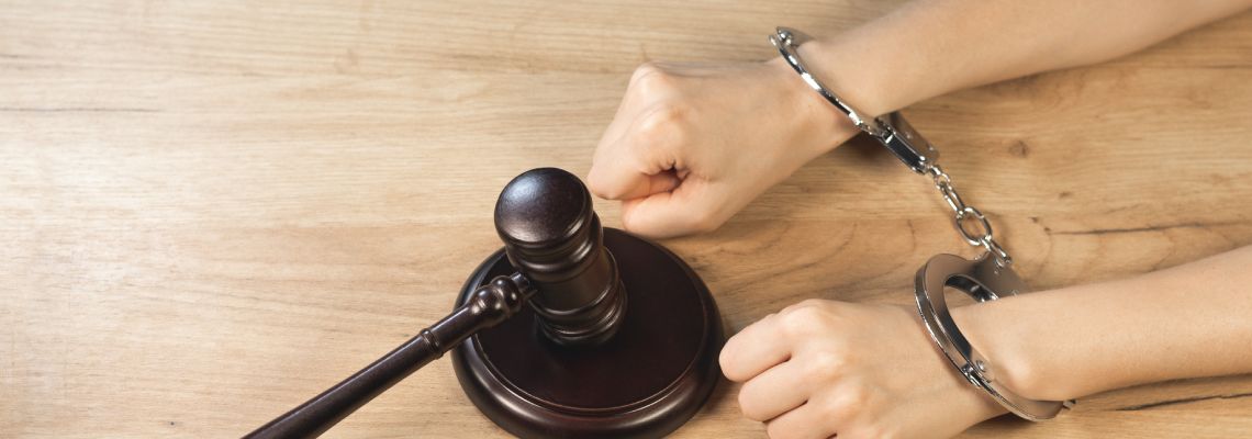 Handcuffed hands and gavel in table