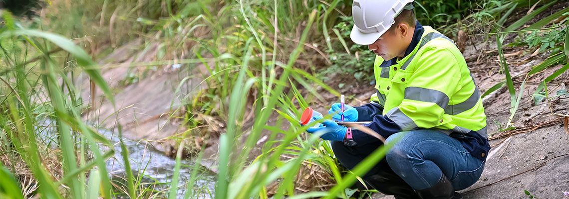 Environmental Inspector Collecting Water Sample from Stream