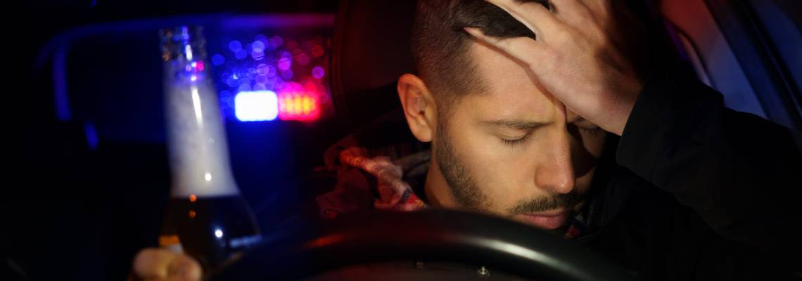 Male driver with beer bottle in hand pulled over by police