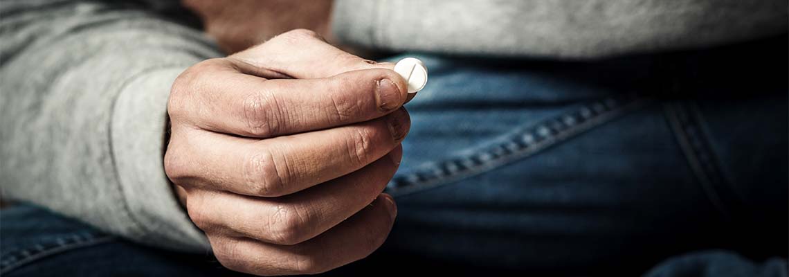 Drug addict holding pills in hand