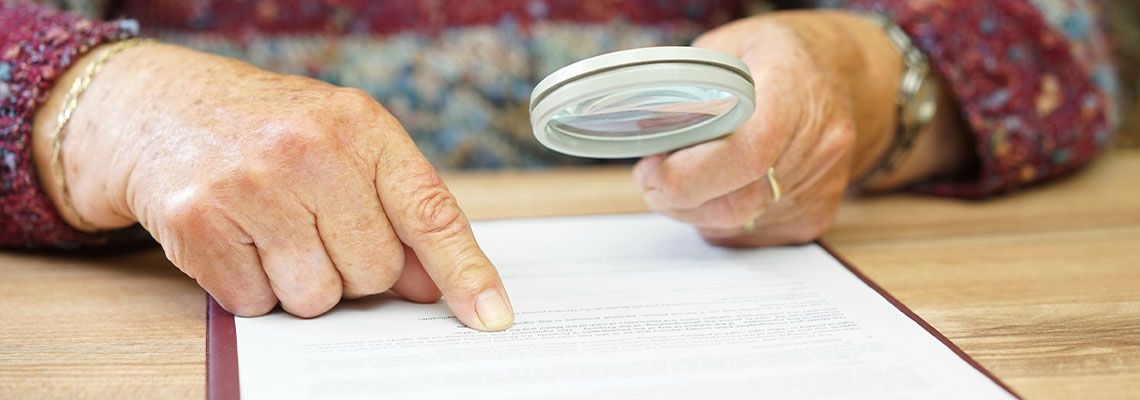 Elderly person with magnifying glass checking Will document