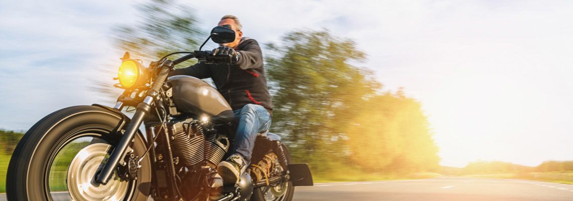 Person riding motorcycle on highway with field in background