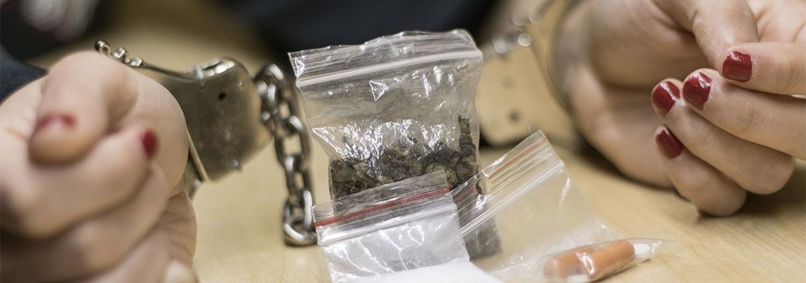 Handcuffed person with drugs on table