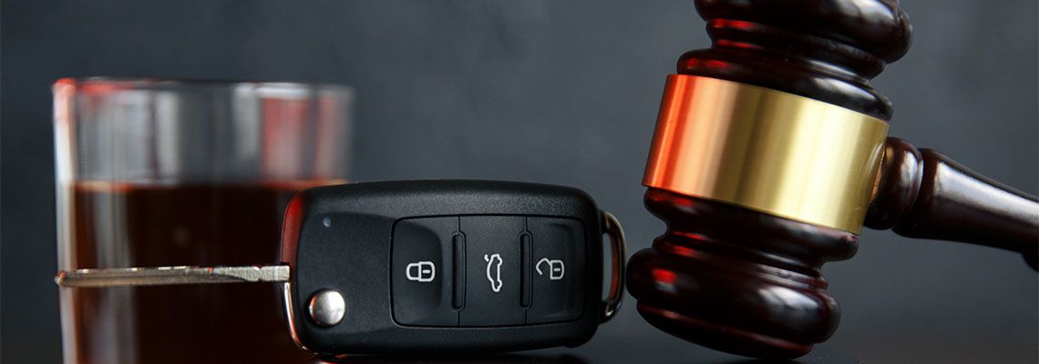 Gavel, alcohol, and car keys on wooden table