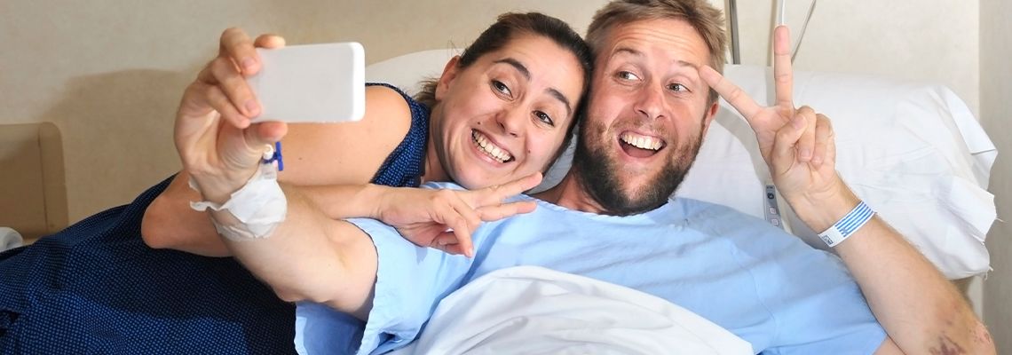 Injured man on hospital bed taking selfie with his wife