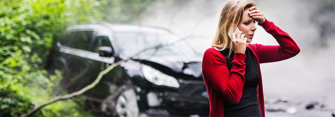 Young woman on phone by the damaged car after car accident