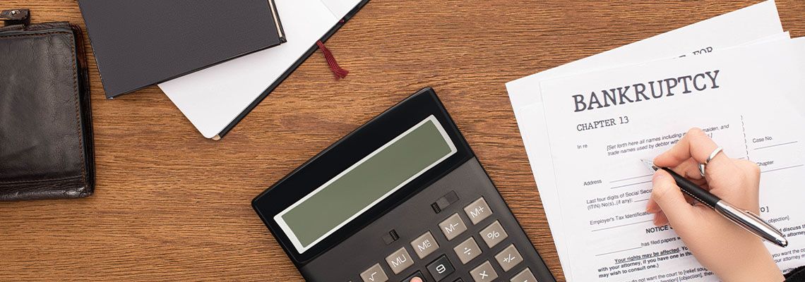Woman completing a bankruptcy form at a desk with a calculator