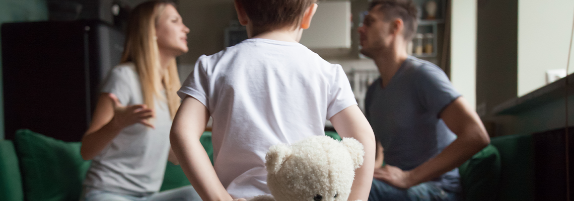 Rear view at kid boy holding toy while parents fighting