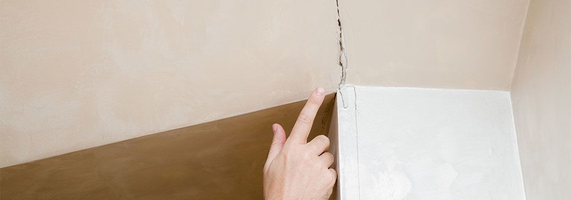 finger pointing to the cracked wall in house