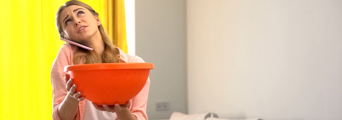 Woman on phone while water leaking from ceiling