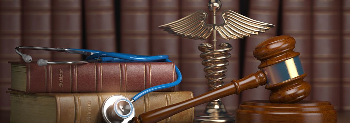 Gavel, stethoscope and caduceus sign on table