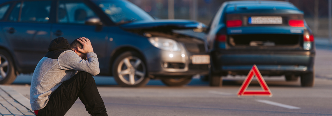 Man sitting on the side of the road after an accident
