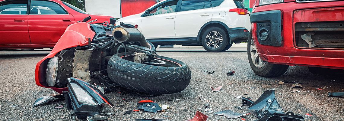 Motorcycle and car crash on road