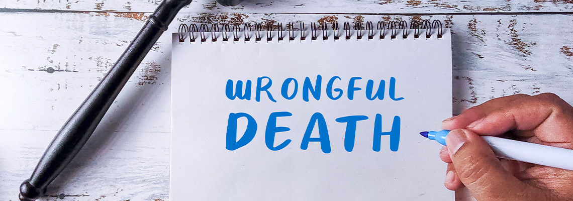 Hand Writing 'Wrongful Death' in a Notebook Next to a Gavel