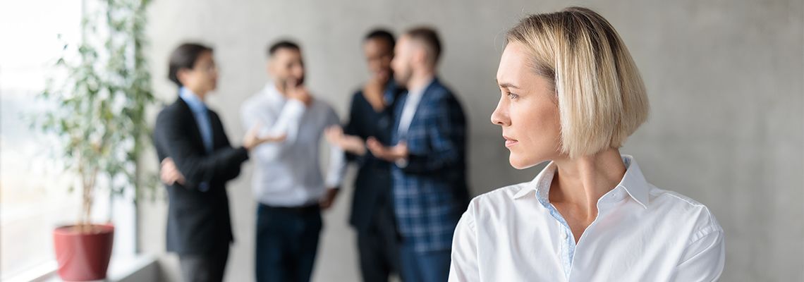 Male Coworkers Whispering Behind Back of Unhappy female colleague