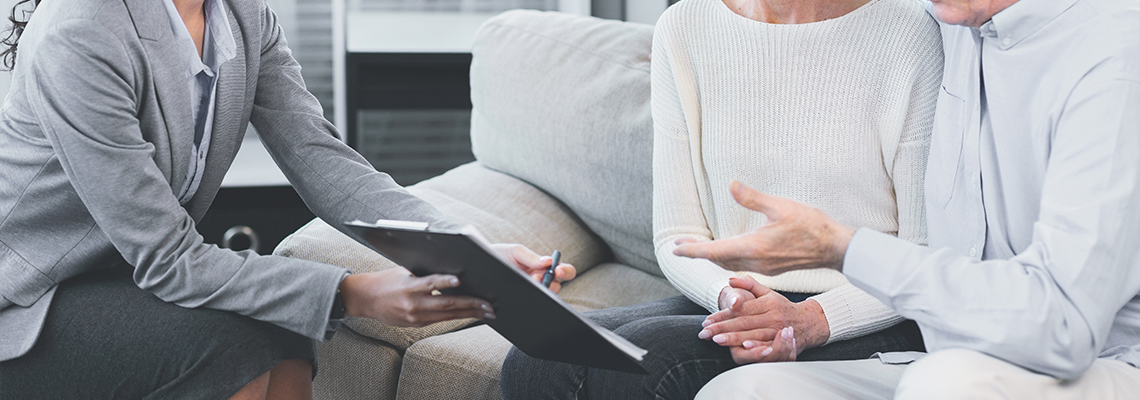 Mature man sitting on couch embracing wife, asking about document
