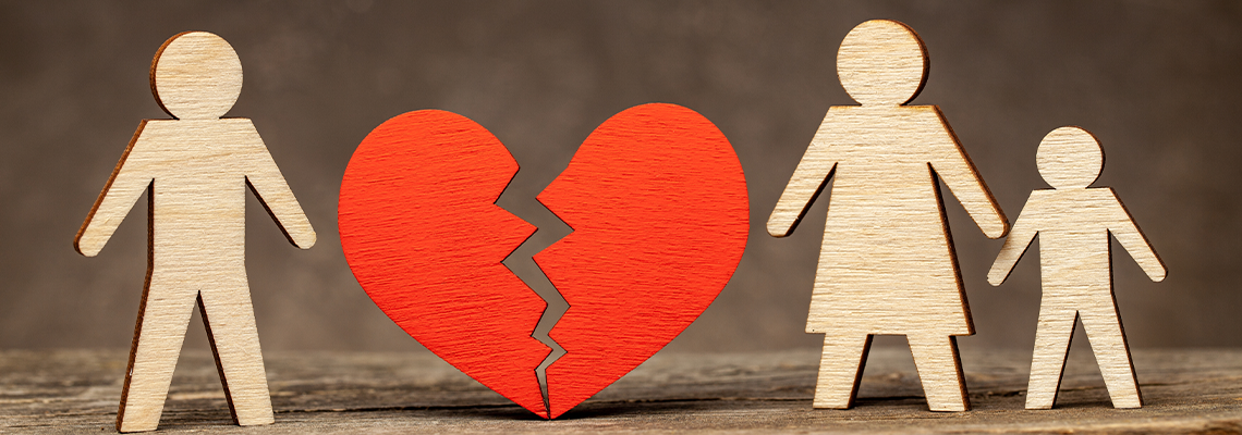 A broken heart in between a husband and a wife with child–wooden cutouts.