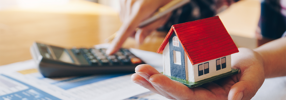 Woman Holding House Model in Hand and Calculating Financial Chart