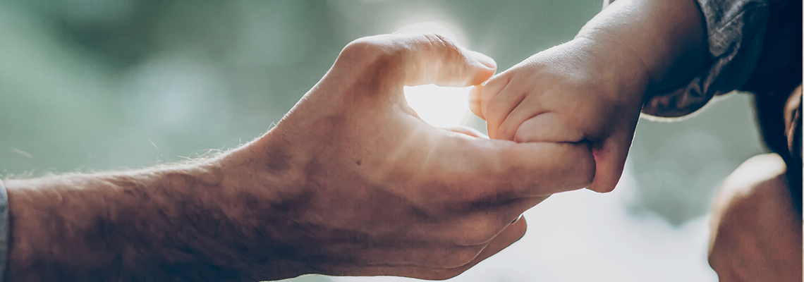 Father and little son holding hands in sunlight