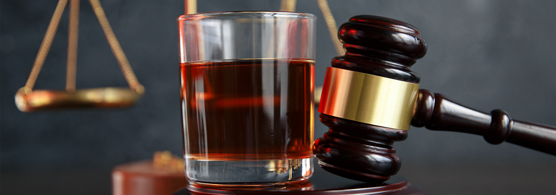 Law hammer, alcohol and car keys on wooden table, dark background