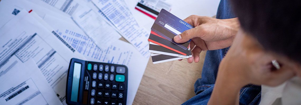 Stressed man with credit card and many bills on floor