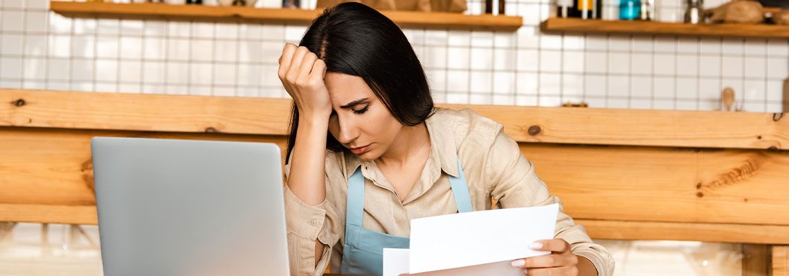 Upset cafe owner holding paper near calculator