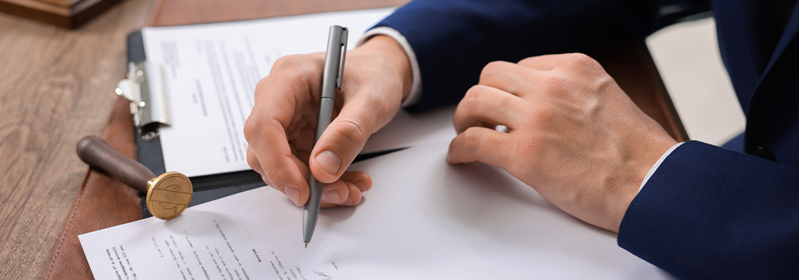 Notary signing document at wooden table in office