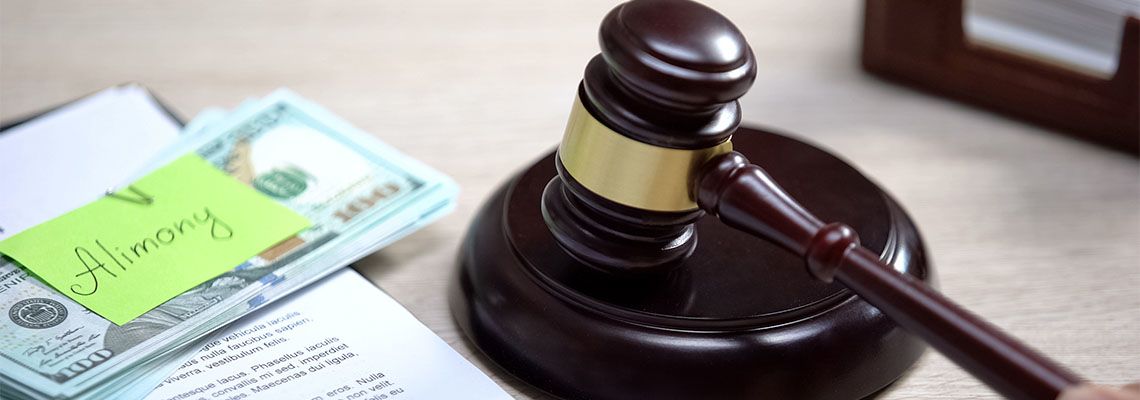 Alimony word in sticky note on top of dollar bill with gavel