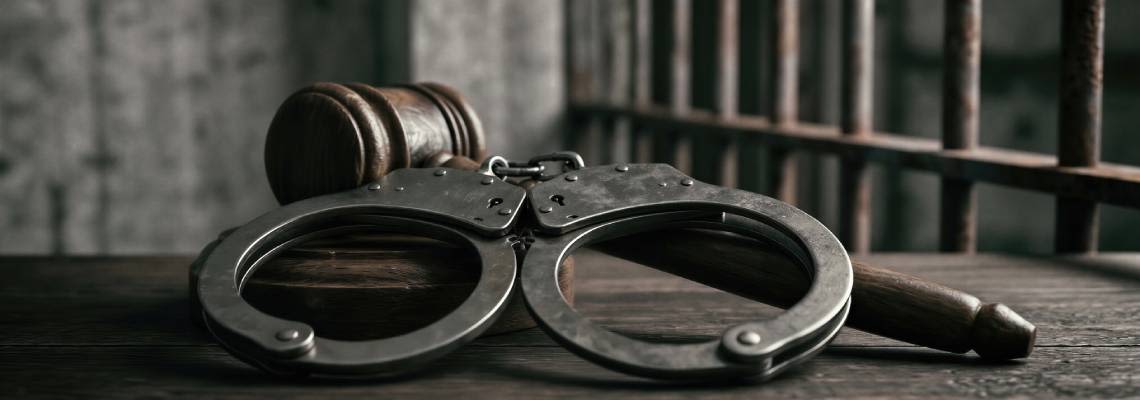 Gavel and Handcuff on table against prison bars